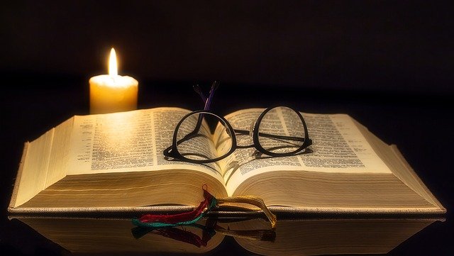 Biblical Declarations - Glasses and Candle On Open Bible 



