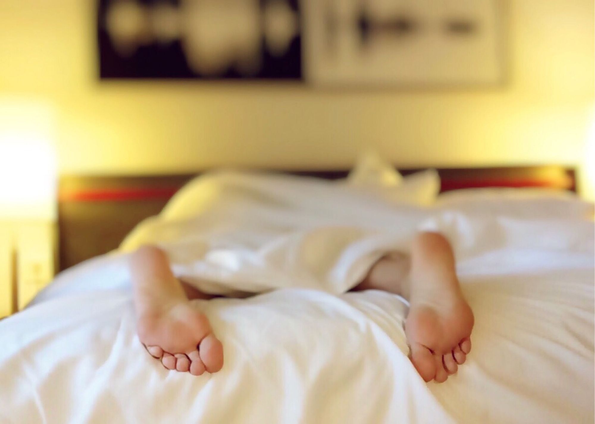 The Benefits of Melatonin - Person's feet Under Covers On Bed 